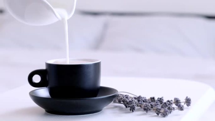 将牛奶倒入热咖啡中。早上早餐概念。床上早餐。在一杯或一杯温暖的卡布奇诺咖啡中添加牛奶