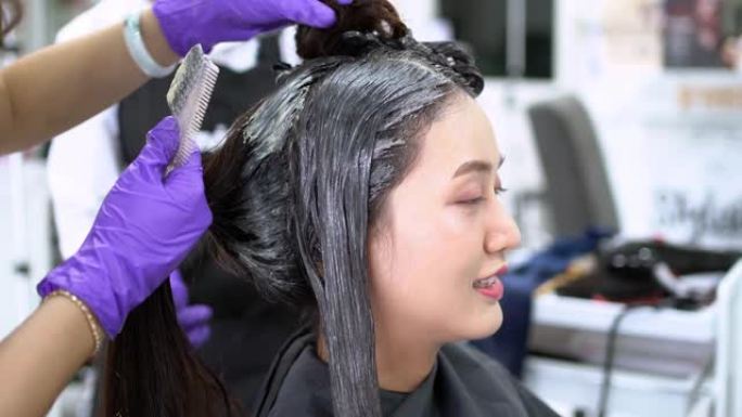 亚洲美容师正在为顾客染发和做头发。在美容院