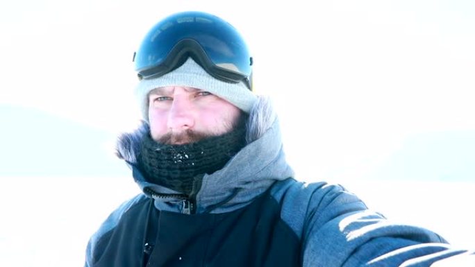 带帽和滑雪板的胡须快乐微笑的男人自拍