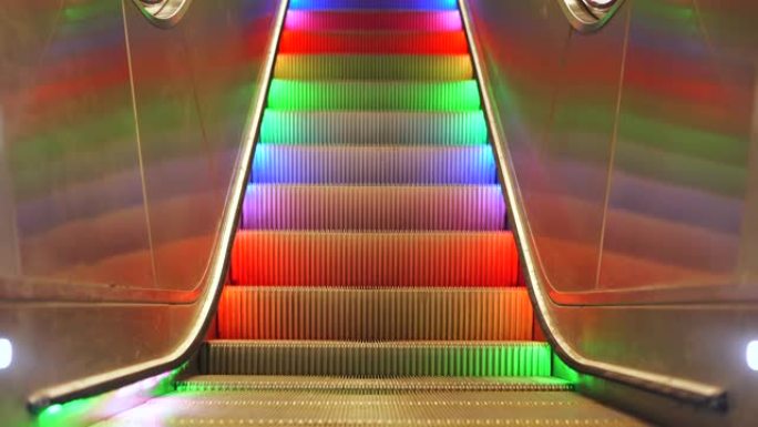 带有多色LED彩虹灯的人行横道自动扶梯无休止地在无人的情况下向下移动。斯德哥尔摩地铁的自动楼梯