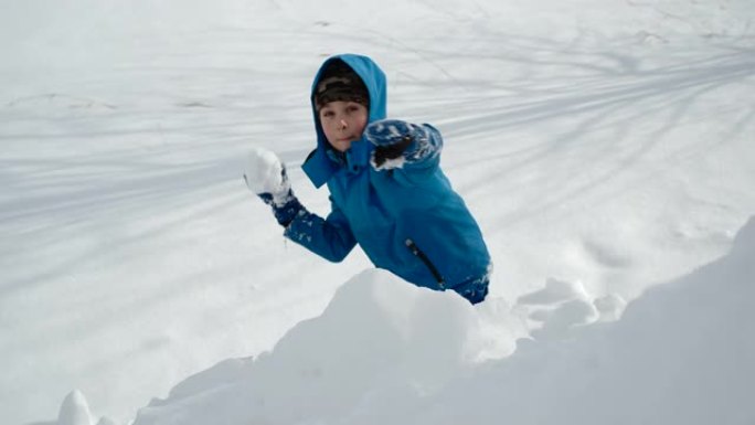 开朗的男孩玩打雪仗玩得开心。慢动作。