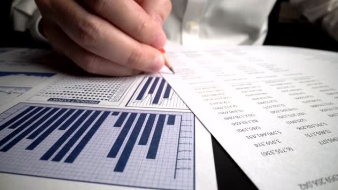会计师在办公桌上的纸质仪表板上分析业务营销数据。