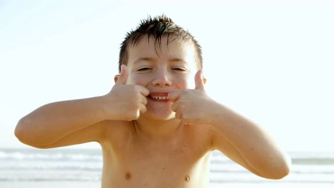 快乐的小男孩在海滩上对着镜头微笑