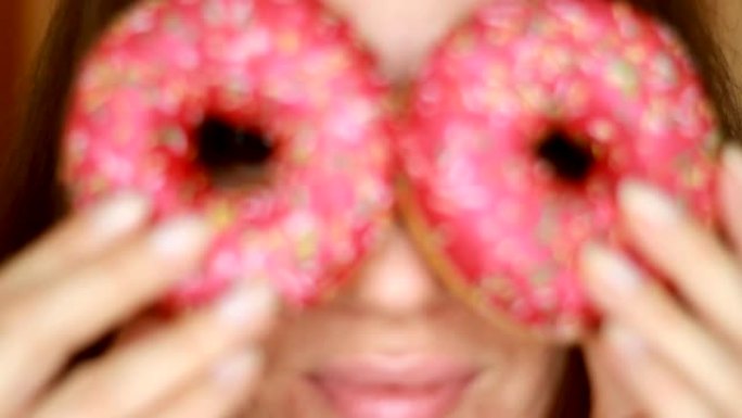 特写女人吃粉红色的甜甜圈，美味，甜，甜食。饮食。节食。选择性聚焦。