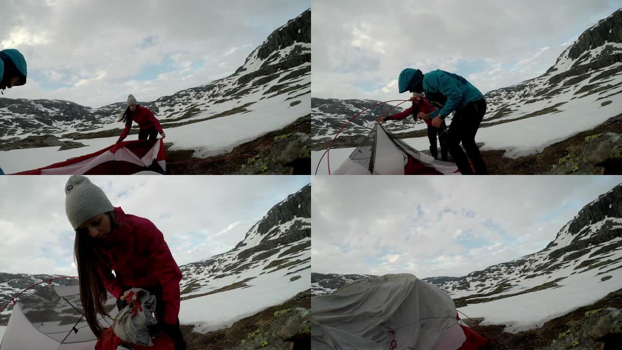 一对年轻夫妇在挪威特罗尔通加附近搭起帐篷。大自然中的野外露营。夫妻玩得很开心。他们被雪包围着。冬季登