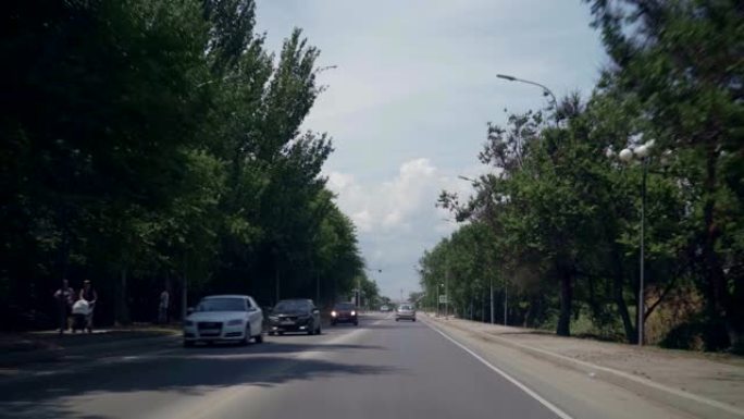 夏天的路，两边是绿树。从车里看。