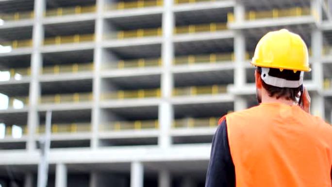 戴着白色头盔的工程师或工人在模糊的建筑工地背景前打电话。