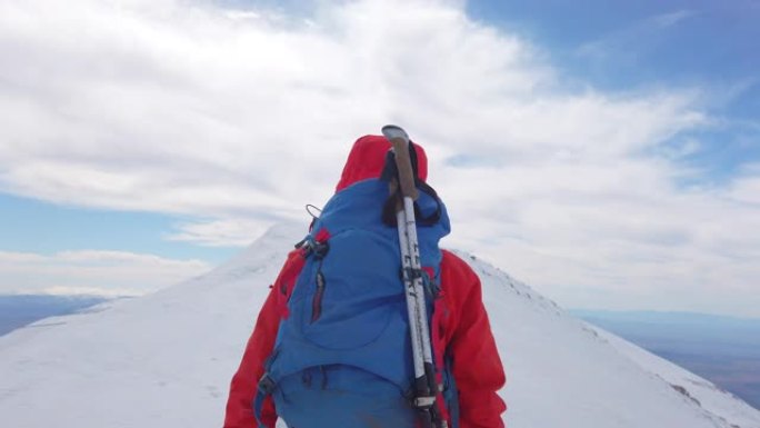 冬季，女性高山登山者与她的团队一起在高海拔的山峰上移动。