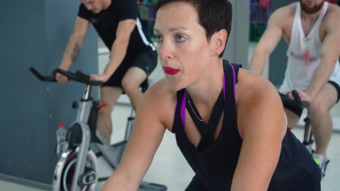 适合女性在自行车课上锻炼室内自行车。健身俱乐部自行车训练中的肖像运动女性。健身人士在体育俱乐部骑自行
