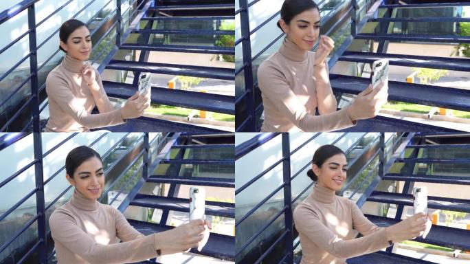 使用智能手机坐在城市台阶上的波斯妇女