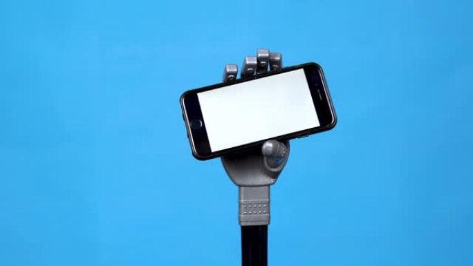 一只机械手拿着一个白色屏幕的电话。灰色半机械手拿着蓝色背景上的智能手机。模板。苹果是一家美国大公司。