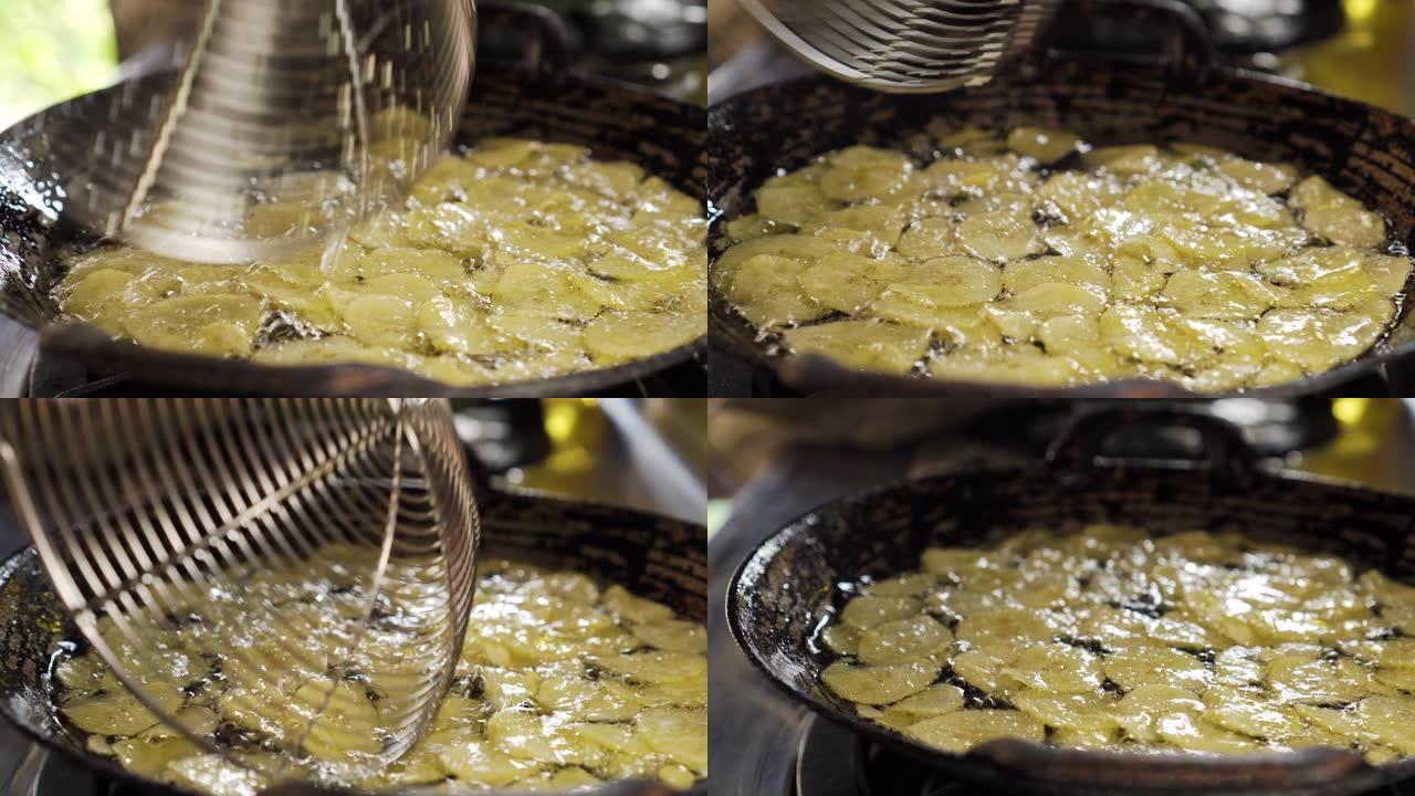 香蕉片在装满油的平底锅上油炸。制作甜香蕉脆。泰国甜点。胖。