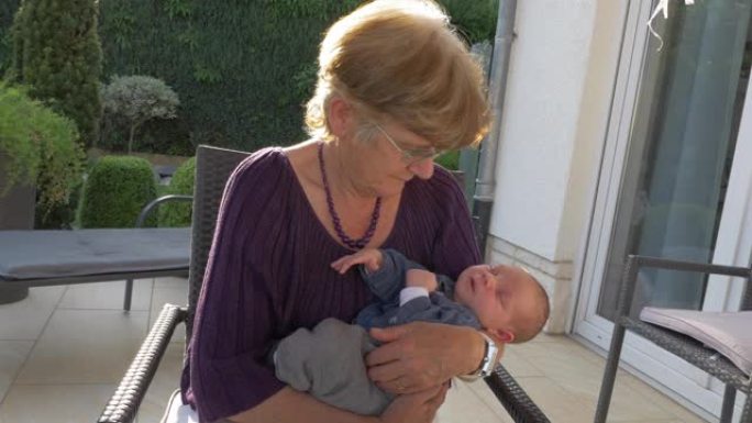 祖母在室外露台上抱着新生婴儿