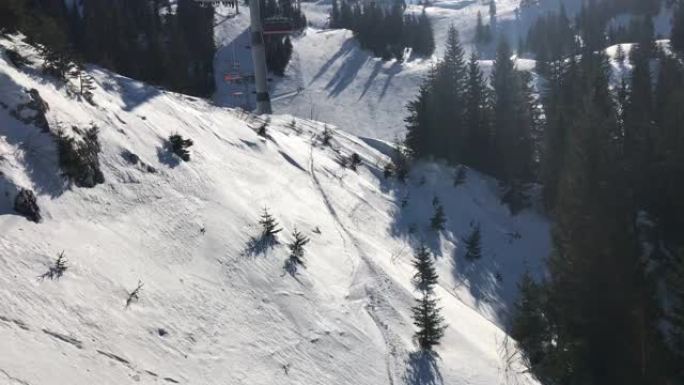 滑雪者在下面的滑雪椅上的鸟瞰图，山坡上风景秀丽的松树