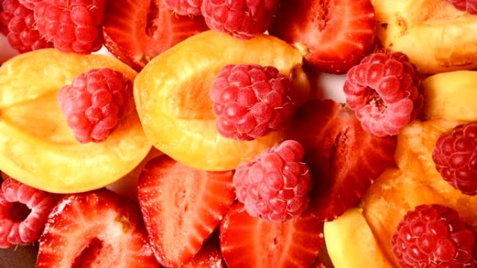 盘子上杏子旁边切成薄片的红色草莓和覆盆子的特写镜头