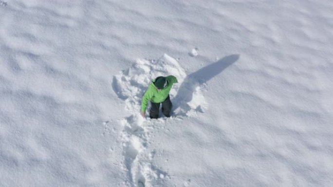 开朗的人害怕，在冬季跑步时在白色的雪堆上逃跑。男子从无人机上坠入雪堆鸟瞰图。顶部鸟瞰图白色蓬松雪中的