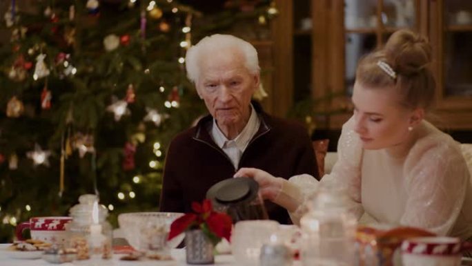 女人在圣诞节期间在杯子里倒黑咖啡给祖父