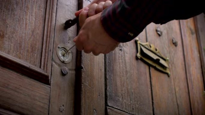 一个男人离开房子并锁上旧木门的低角度