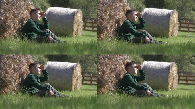 一个小男孩看着坐在草地上的阳光。
