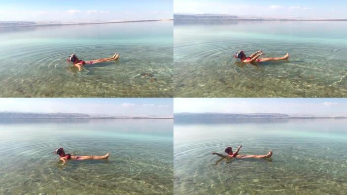 女人在死海中游泳，有趣，躺在背上，手机旅行镜头