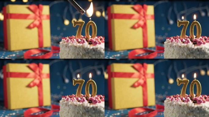 白色生日蛋糕70号点火器燃烧的金色蜡烛，蓝色背景带灯和用红丝带捆绑的礼物黄色盒子。特写
