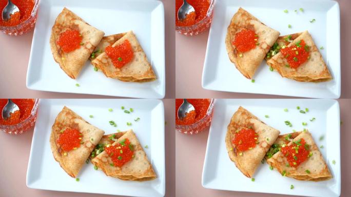用红色鱼子酱将葱滴到俄罗斯薄饼上的慢动作视频