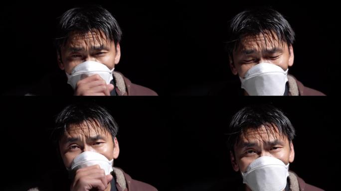 生病的亚洲男子在黑色背景下戴着医用口罩咳嗽