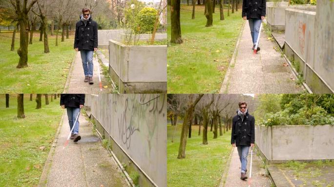 年轻英俊的盲人拄着白色拐杖在公园里散步