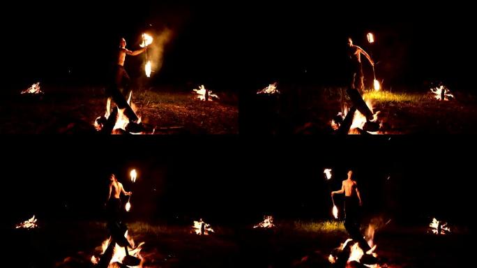 低调。一名长发，裸露躯干的年轻男性在大火附近的黑色夜晚视频慢动作中在户外旋转燃烧的火炬。现代法克尔 