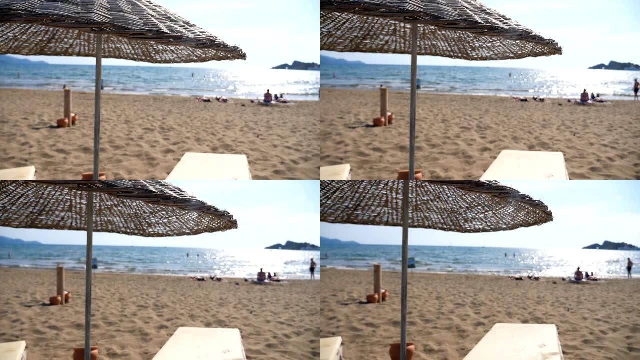 夏日，海景和沙滩的美丽景色，配有稻草太阳伞。海边附近有躺椅的舒适场所。海洋海岸附近平静的田园风光。慢