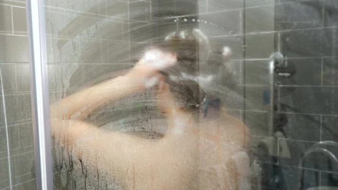 模糊裸女在玻璃后面用泡沫洗发水洗头