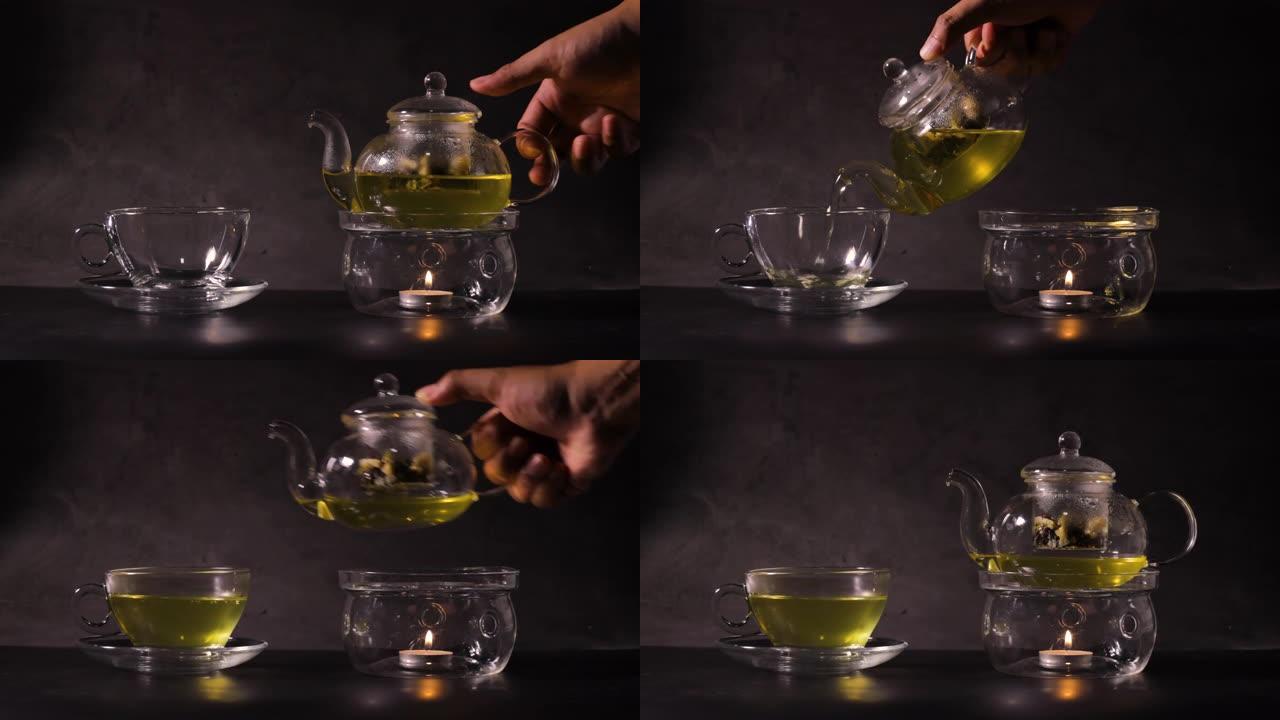 男人双手握着茶壶，将热绿茶倒入厨房的茶杯中。经典茶壶由玻璃和蜡烛烧开水制成。热饮和茶时间概念。