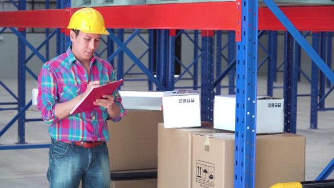 亚洲男子工头看着顶部货架上的纸盒，用于检查仓库中的货物