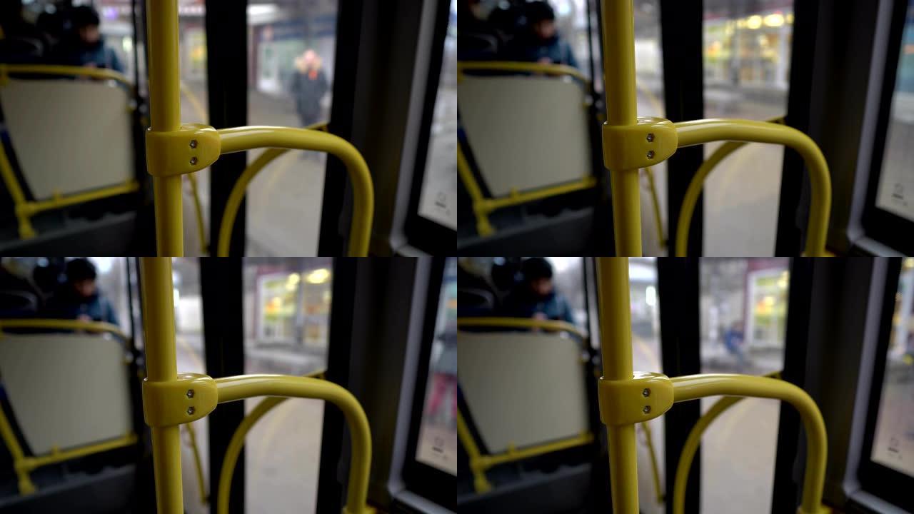 从穿过城市的公共汽车内部观看。黄色扶手的特写镜头，然后是公共汽车内饰和玻璃门的模糊视图。抽象。4K