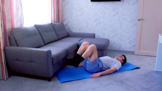有趣的书呆子男人躺在家里的垫子上抬腿。运动幽默概念。