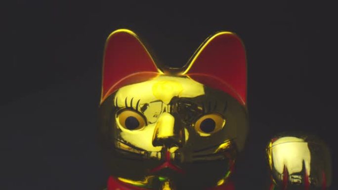 金色闪亮的中国幸运猫的特写镜头挥舞着一只爪子，背景孤立在黑色