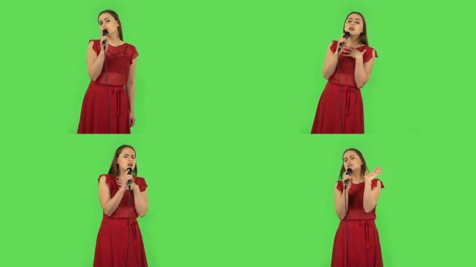 穿着红色连衣裙的温柔女孩正在对着麦克风唱歌，随着音乐的节奏而移动。绿屏