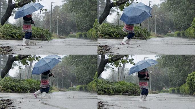 一个小女孩在水坑里跳伞的慢动作在雨中撑着伞