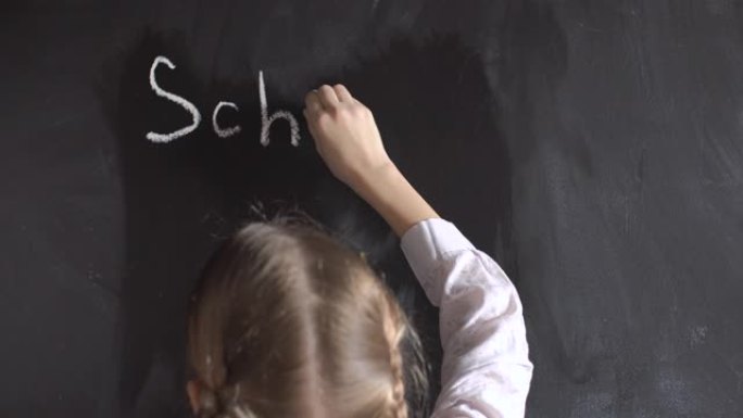 小女孩在黑板上写下学校这个词。