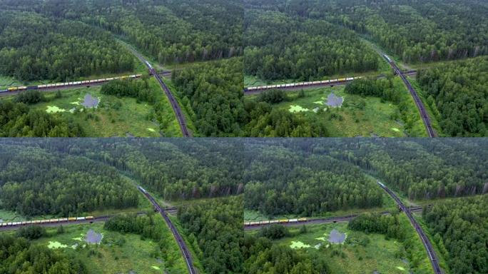 两列货运列车的鸟瞰图在森林中央以直角交叉，毗邻沼泽湖。乌拉尔山脉的美丽自然，穿越铁轨。
