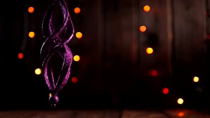木制背景上的圣诞紫色闪亮玩具，闪烁彩灯。