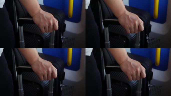 在机场排队的一名妇女拿着手提箱的把手的特写镜头。旅游和旅游的概念