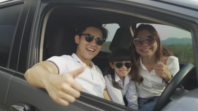 快乐的亚洲家庭，父亲竖起大拇指，母女俩在紧凑型汽车上戴着太阳镜，微笑着开车去度假。汽车保险或租赁和家