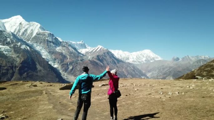 一对夫妇在前往尼泊尔喜马拉雅山安纳普尔纳巡回赛的一部分冰湖的路上跳舞。他们玩得很开心。后面覆盖着雪的