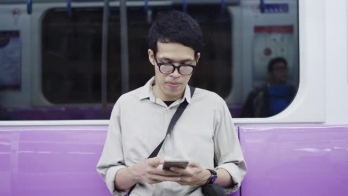 年轻的亚洲男子在乘坐地铁时使用智能手机