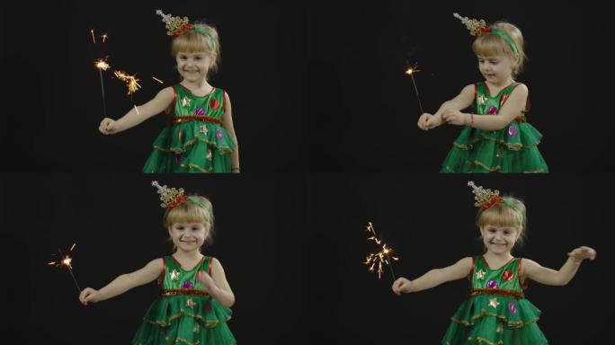 穿着圣诞树服装的快乐美丽女婴。燃烧的孟加拉灯