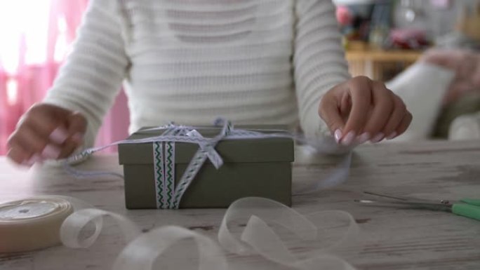 面目全非的年轻女子解开圣诞礼品盒上的丝带