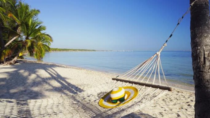 海边热带海滩上棕榈树之间的空吊床