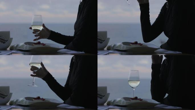 女人在海景餐厅喝白葡萄酒