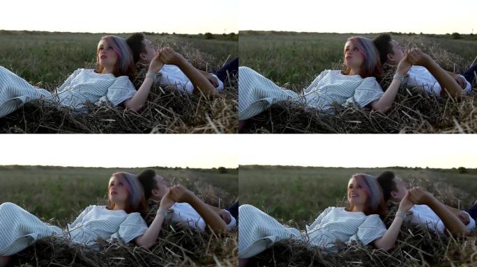 慈爱的男人和女人躺在干草上牵着手